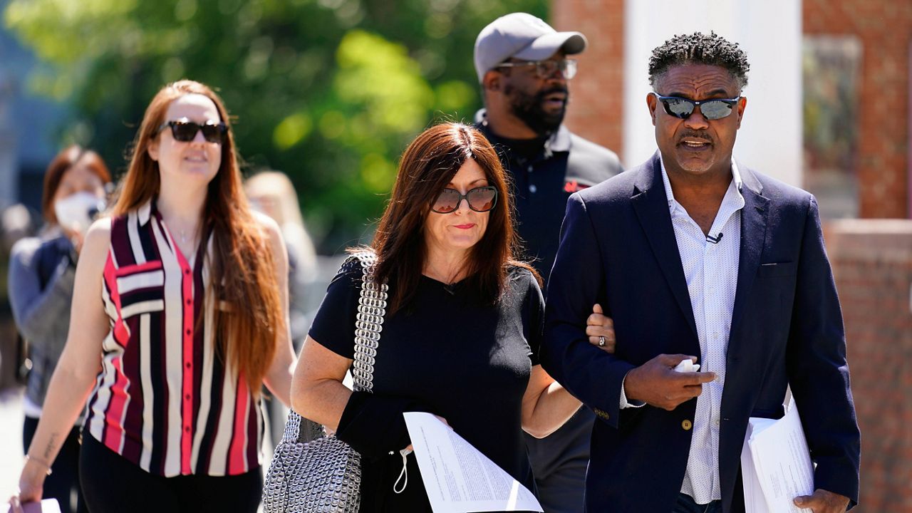 In this May 14, 2021, file photo, former NFL players Ken Jenkins, right, and Clarence Vaughn III, center right, along with their wives, carry petitions to the federal courthouse in Philadelphia demanding equal treatment for everyone involved in the settlement of concussion claims against the NFL. (AP Photo/Matt Rourke, File)