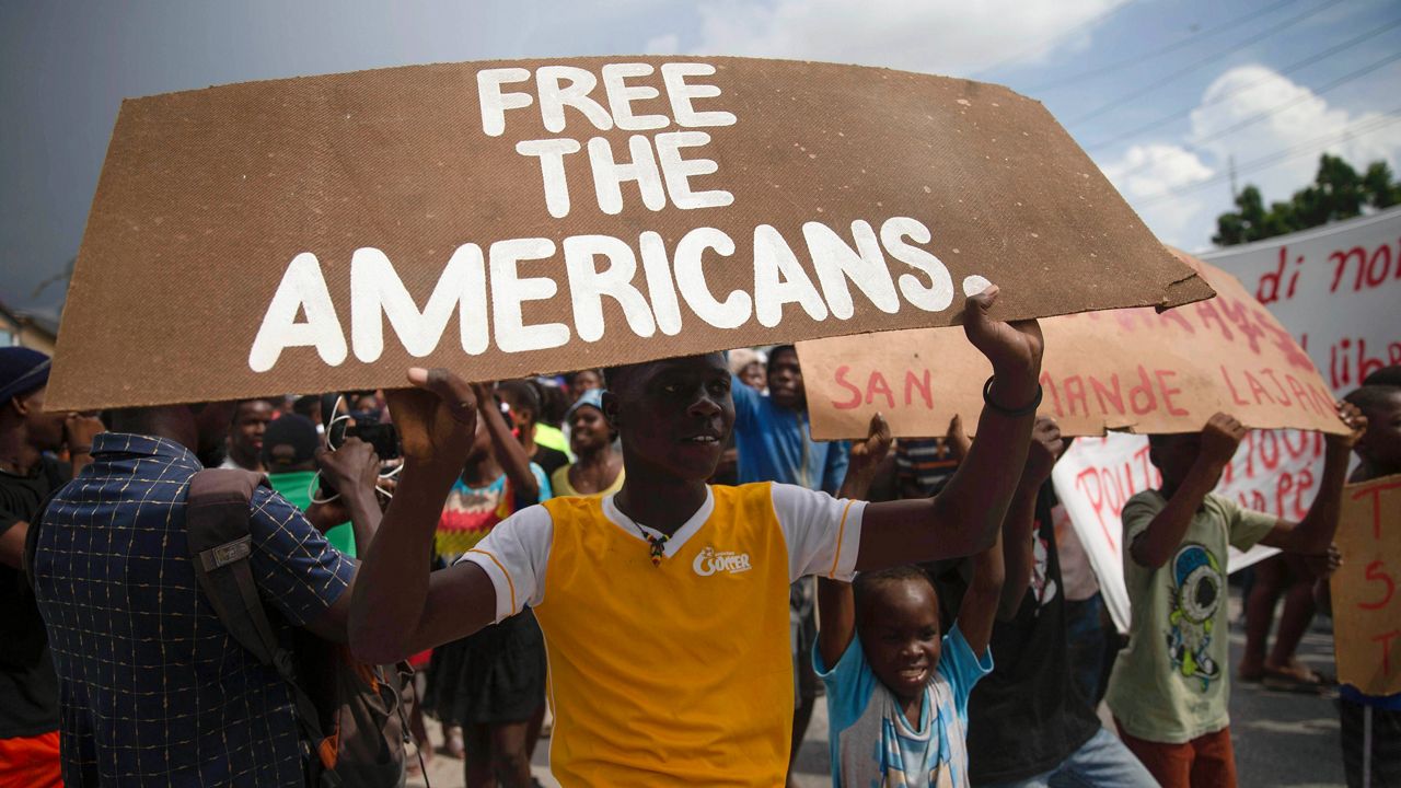 People protest for the release of kidnapped missionaries Tuesday near the Ohio-based Christian Aid Ministries headquarters in Titanyen, north of Port-au-Prince, Haiti. (AP Photo/Joseph Odelyn)