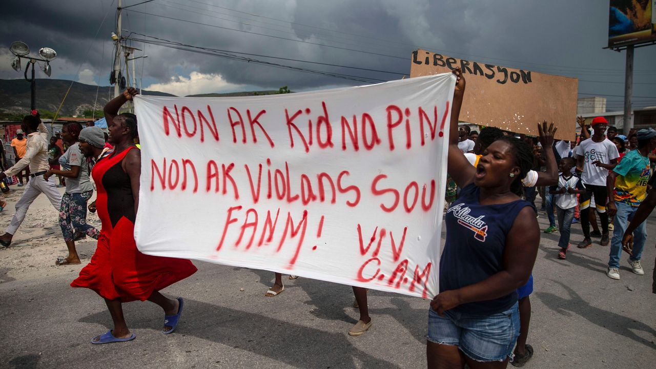 People protest carrying a banner with a message that reads in Creole: "No to kidnappings, no to violence against women ! Long live Christian Aid Ministries," demanding the release of kidnapped missionaries, in Titanyen, north of Port-au-Prince, Haiti, Tuesday, Oct. 19, 2021. (AP Photo/Joseph Odelyn)