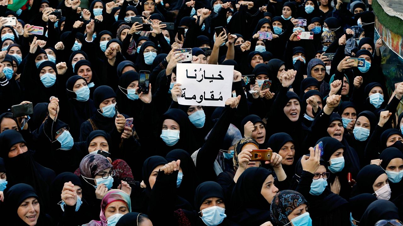 Mourners chant slogans Oct. 15 as they hold a placard with Arabic that reads "Our choice is resistance" during the funeral of three Hezbollah supporters who were killed during clashes, in the southern Beirut suburb of Dahiyeh, Lebanon. (AP Photo/Bilal Hussein, File)