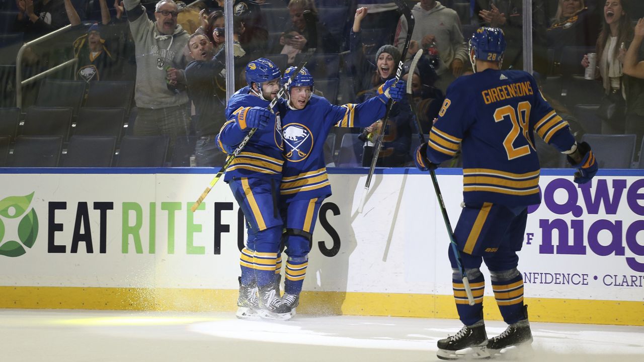 Buffalo Sabres center Drake Caggiula, center, celebrates with defenseman Will Butcher, left, after scoring a goal during the second period of an NHL hockey game against the Tampa Bay Lightning, Monday, Oct. 25, 2021, in Buffalo, N.Y. (AP Photo/Joshua Bessex)