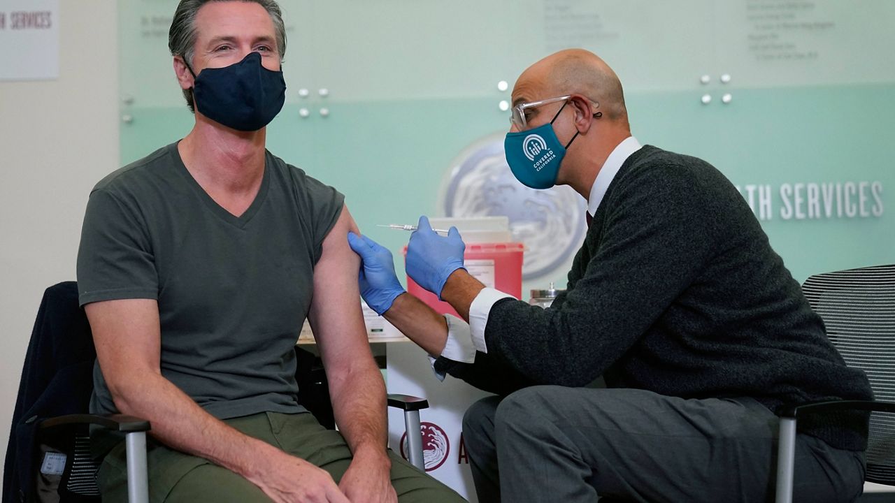 Gov. Gavin Newsom, left, receives a Moderna COVID-19 vaccine booster shot from California Health and Human Services Secretary Dr. Mark Ghaly at Asian Health Services in Oakland, Calif., Wednesday, Oct. 27, 2021. (AP Photo/Jeff Chiu)