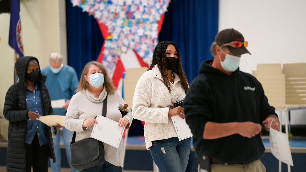 Voters hold their ballots as they wait in line to register their votes at a school in Midlothian, Va., Tuesday, Nov. 2, 2021. (AP Photo/Steve Helber)