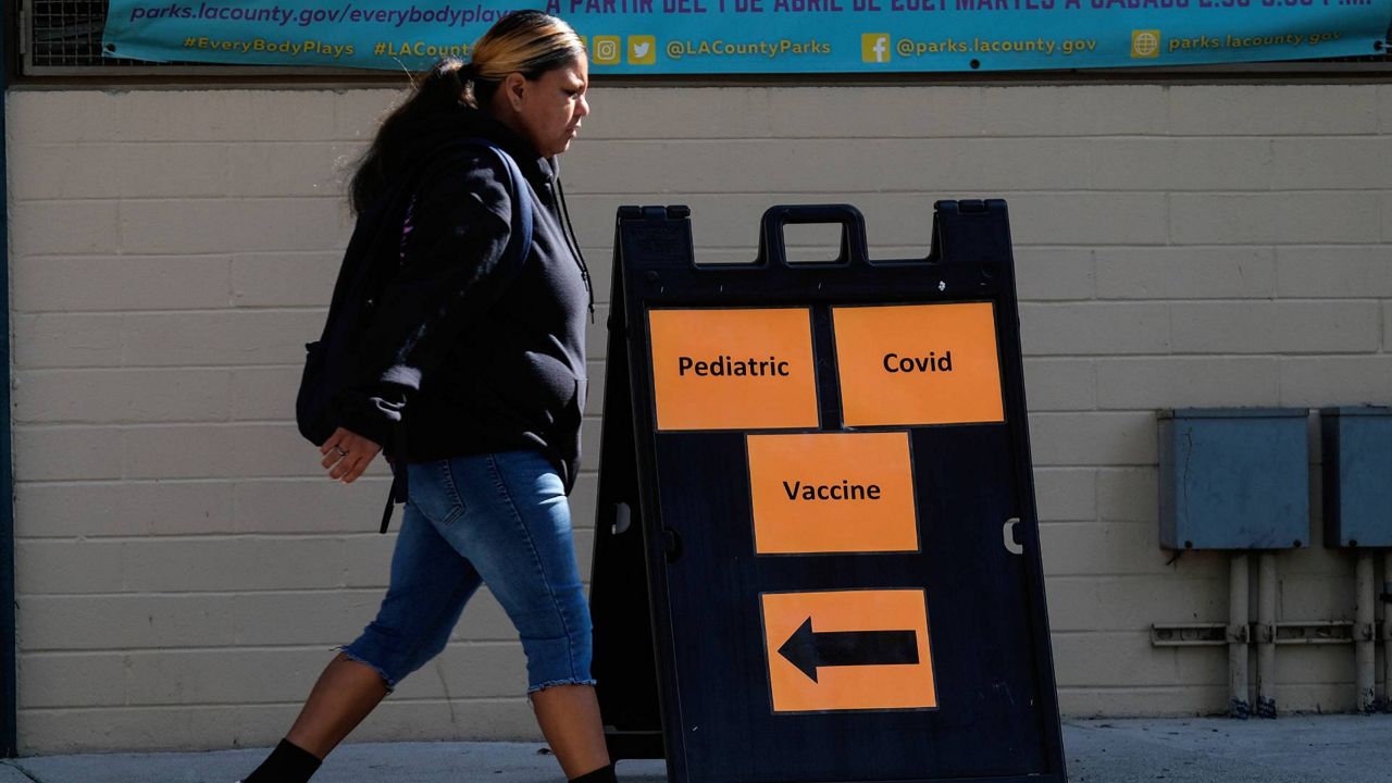 A woman walks by a sign reading: "Pediatric Covid Vaccine" outside a COVID-19 vaccine center in Los Angeles, on Wednesday, Nov. 3, 2021. (AP Photo/Ringo H.W. Chiu)