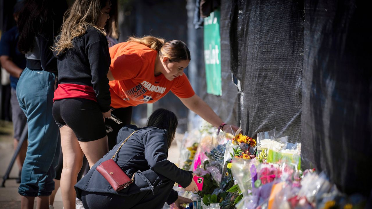 Stacey Sarmiento places flowers at a memorial in Houston on Sunday in memory of her friend, Rudy Pena, who died in a crush of people at the Astroworld music festival on Friday. (AP Photo/Robert Bumsted)