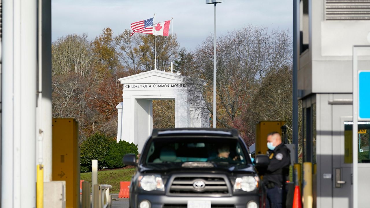 A U.S. Customs and Border Protection officer checks identification on a driver entering the U.S. from Canada at the Peace Arch border crossing Monday, Nov. 8, 2021, in Blaine, Wash. (AP Photo/Elaine Thompson)