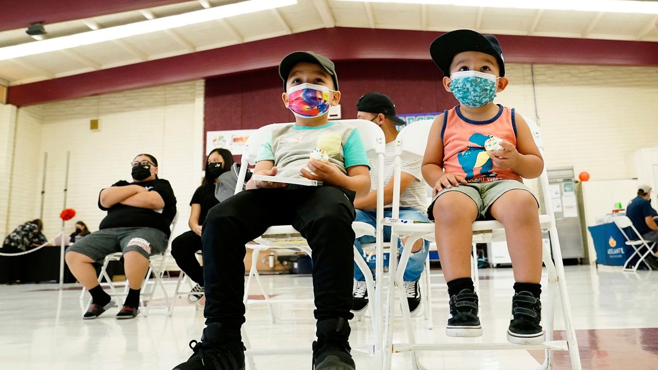 FILE - Oliver Estrada, 5, front left, waits with his brother Adriel, 2, after Estrada received the first dose of the Pfizer COVID-19 vaccine at an Adelante Healthcare community vaccine clinic at Joseph Zito Elementary School, Nov. 6, 2021, in Phoenix. (AP Photo/Ross D. Franklin, File)