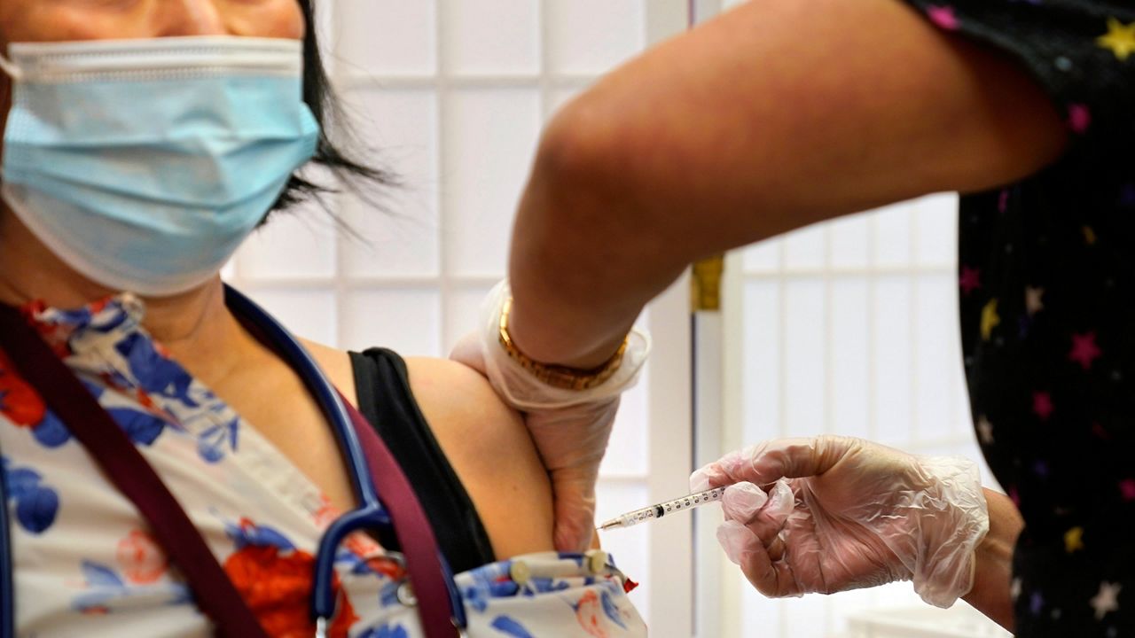 FILE — Cristina Licup receives her COVID-19 booster shot where she works at the Hebrew Home at Riverdale in New York, Sept. 27, 2021. (AP Photo/Seth Wenig)