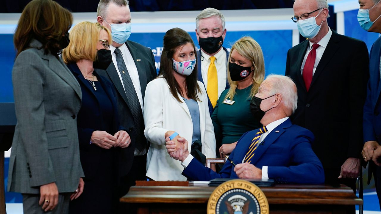 President Joe Biden shakes hands with Kelly Stuart before signing a law named after her father S.1095, “Colonel John M. McHugh Tuition Fairness for Survivors Act of 2021” during a ceremony in the South Court Auditorium on the White House campus, Tuesday, Nov. 30, 2021, in Washington. (AP Photo/Evan Vucci)