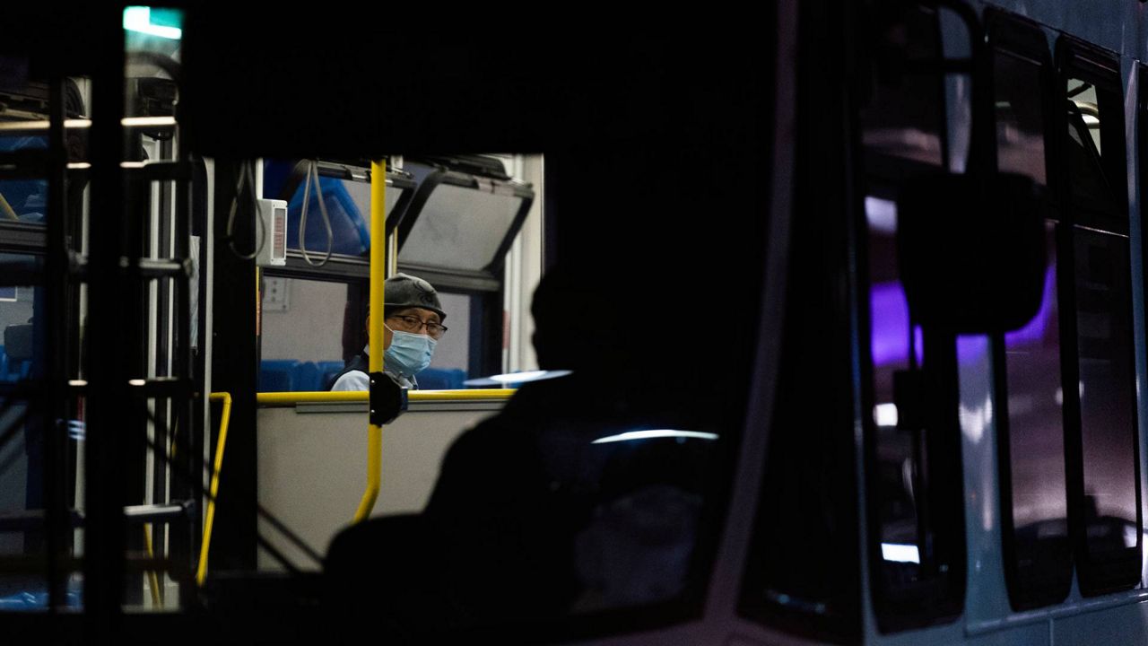 A traveler wearing a protective face mask sits in a shuttle bus at the Los Angeles International Airport, Nov. 30, 2021. (AP Photo/Jae C. Hong)