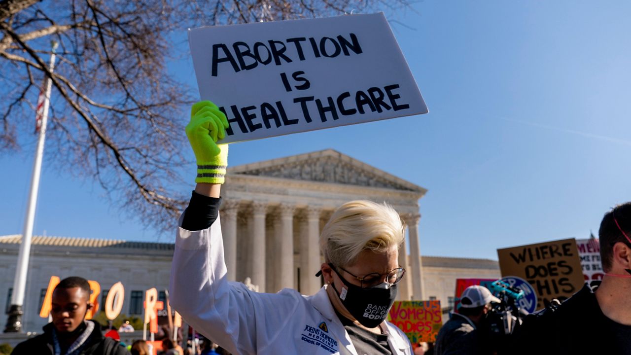FILE - A woman holds a poster that reads "Abortion is Healthcare" as abortion rights advocates and anti-abortion protesters demonstrate in front of the U.S. Supreme Court, Dec. 1, 2021, in Washington, as the court hears arguments in a case from Mississippi, where a 2018 law would ban abortions after 15 weeks of pregnancy, well before viability. (AP Photo/Andrew Harnik, File)