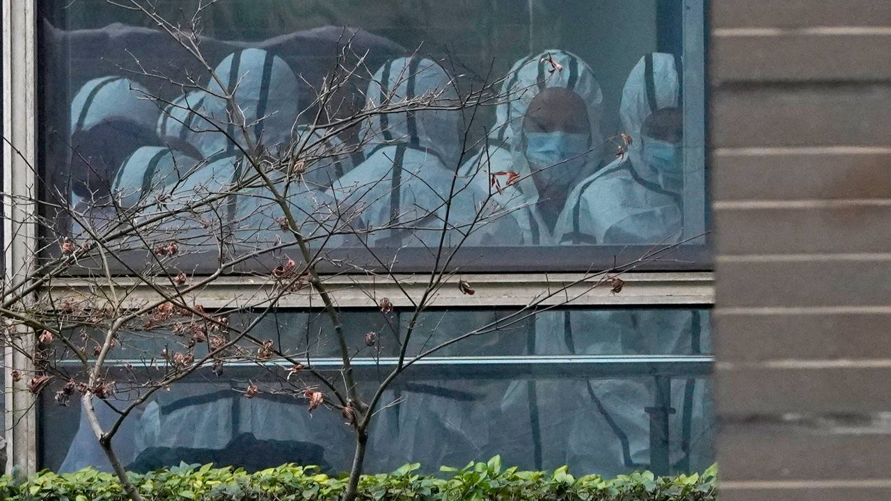Members of a WHO team are seen through a window wearing protective gear during a field visit to the Hubei Animal Disease Control and Prevention Center in Wuhan, China, on Feb. 2. (AP Photo/Ng Han Guan, File)