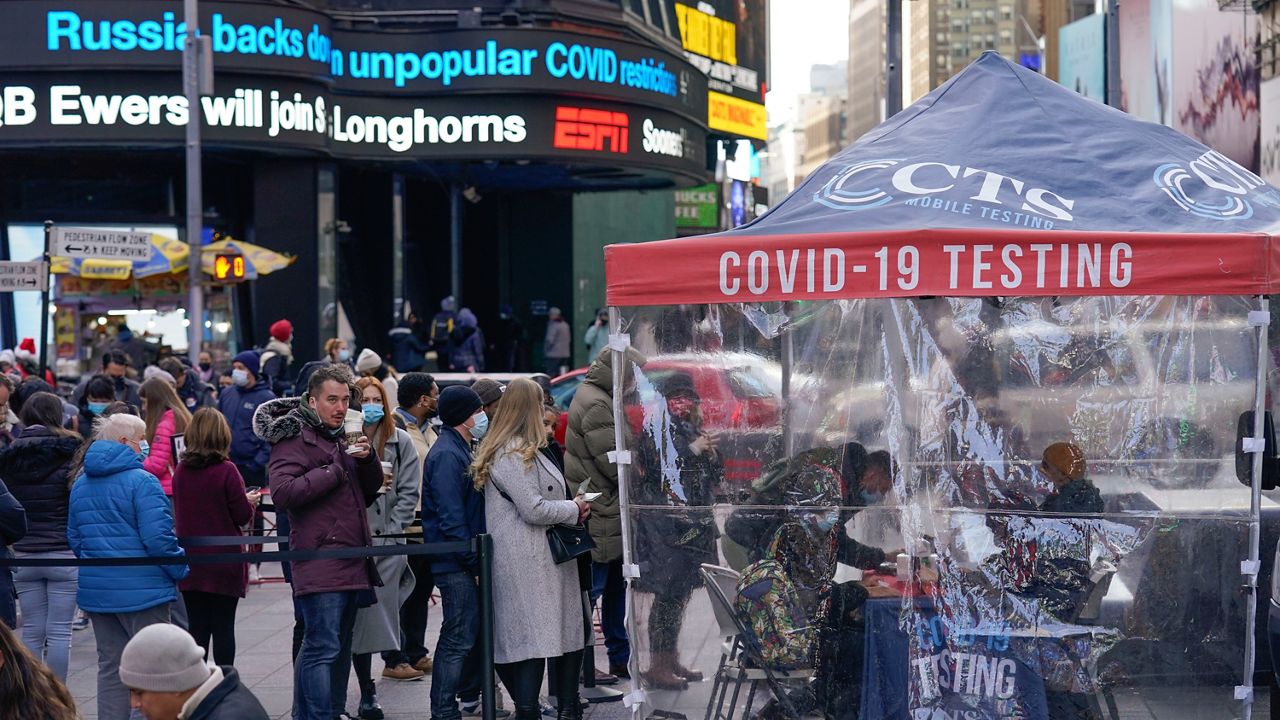 People wait in line at a COVID-19 testing site in Times Square, New York, Monday, Dec. 13, 2021. A mask mandate for shops and other indoor spaces in New York state took effect Monday as officials confront a surge in COVID-19 cases and hospitalizations. (AP Photo/Seth Wenig)