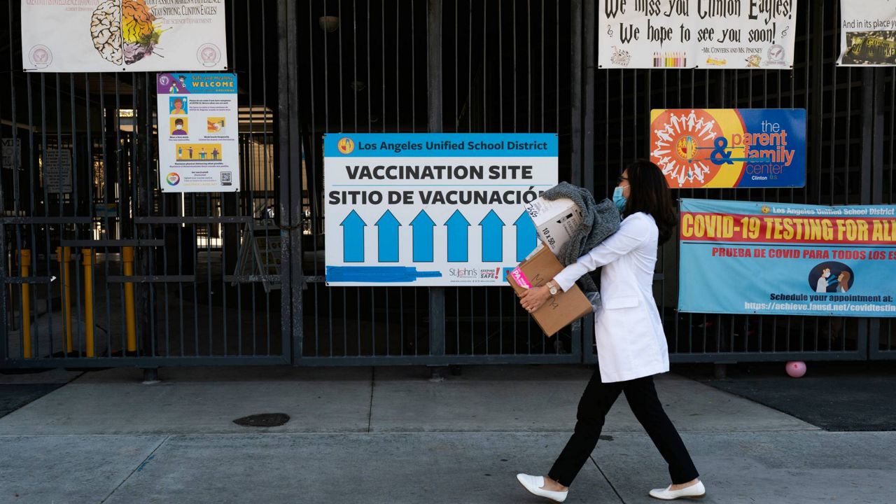 Pharmacist Erica Jing arrives at William Jefferson Clinton Middle School to set up a pop-up COVID-19 vaccination site for students in Los Angeles, Dec. 15, 2021. (AP Photo/Jae C. Hong)