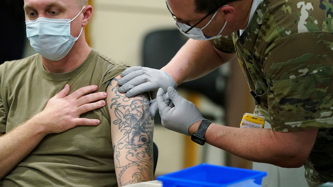 FILE - Staff Sgt. Travis Snyder, left, receives the first dose of the Pfizer COVID-19 vaccine given at Madigan Army Medical Center at Joint Base Lewis-McChord in Washington state, Dec. 16, 2020, south of Seattle. (AP Photo/Ted S. Warren, File)