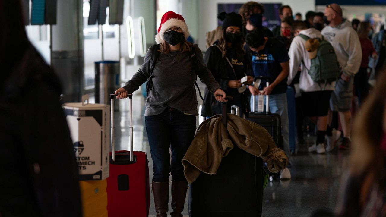 Donning a Santa Claus hat, Caitlin Banford waits in line to check in for her flight to Washington at Los Angeles International Airport in Los Angeles, Dec. 20, 2021. (AP Photo/Jae C. Hong)