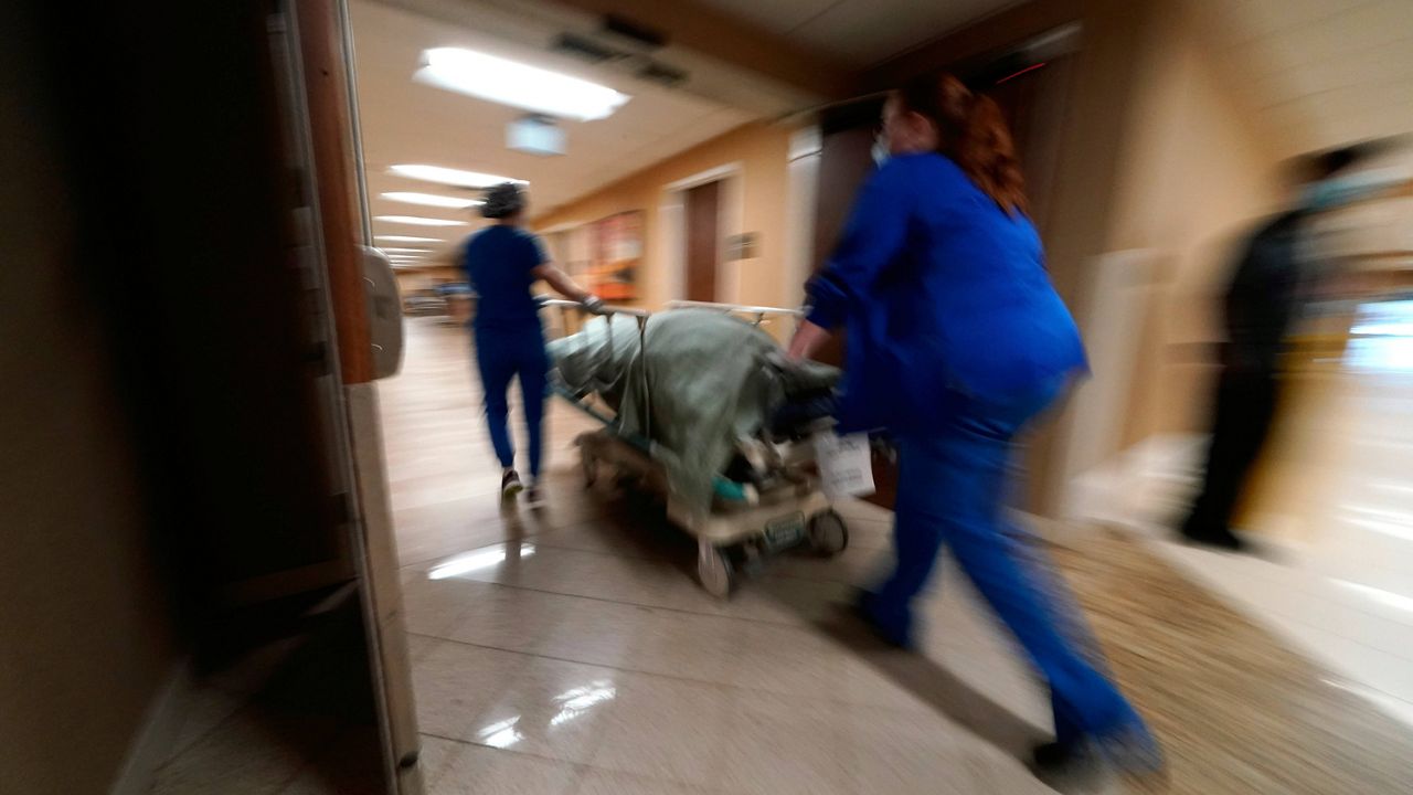 Medical staff move a COVID-19 patient who died to a loading dock to hand off to a funeral home van at the Willis-Knighton Medical Center in Shreveport, La. (AP Photo/Gerald Herbert, File)