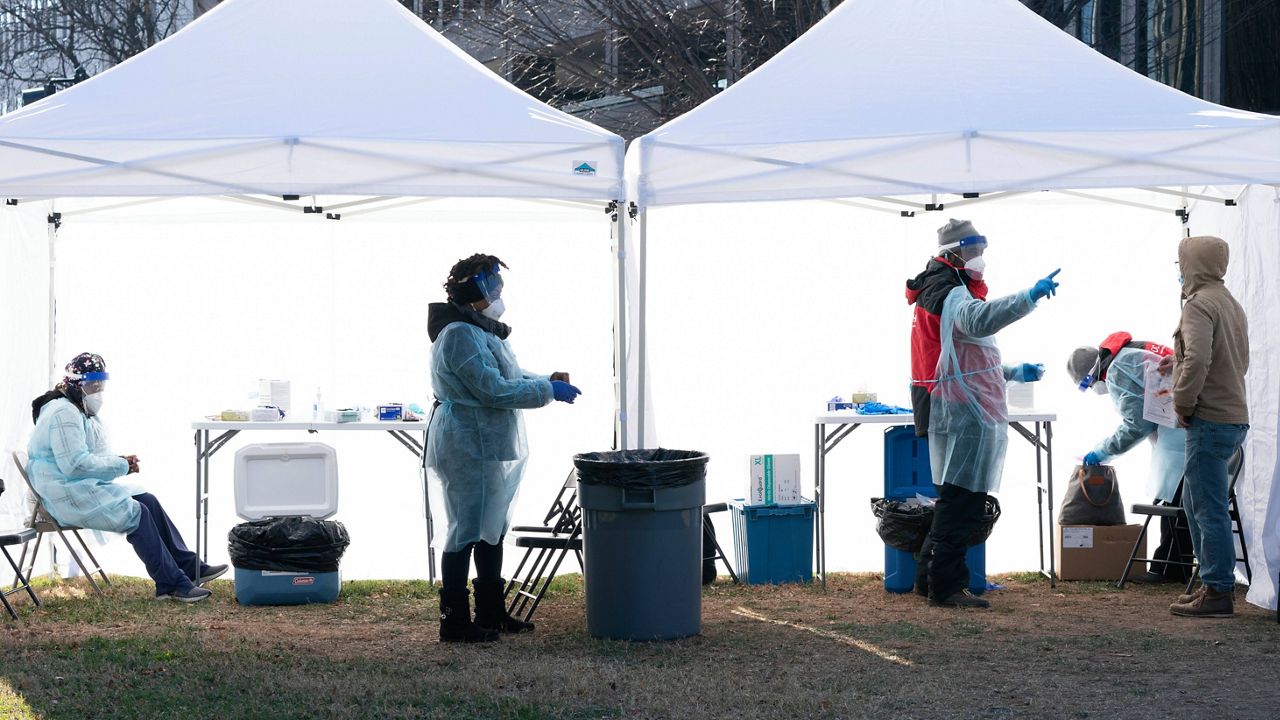 Workers change their medical gloves Thursday as people are tested for COVID-19 at a walk-up testing site at Farragut Square, just blocks from the White House in Washington. (AP Photo/Jacquelyn Martin)