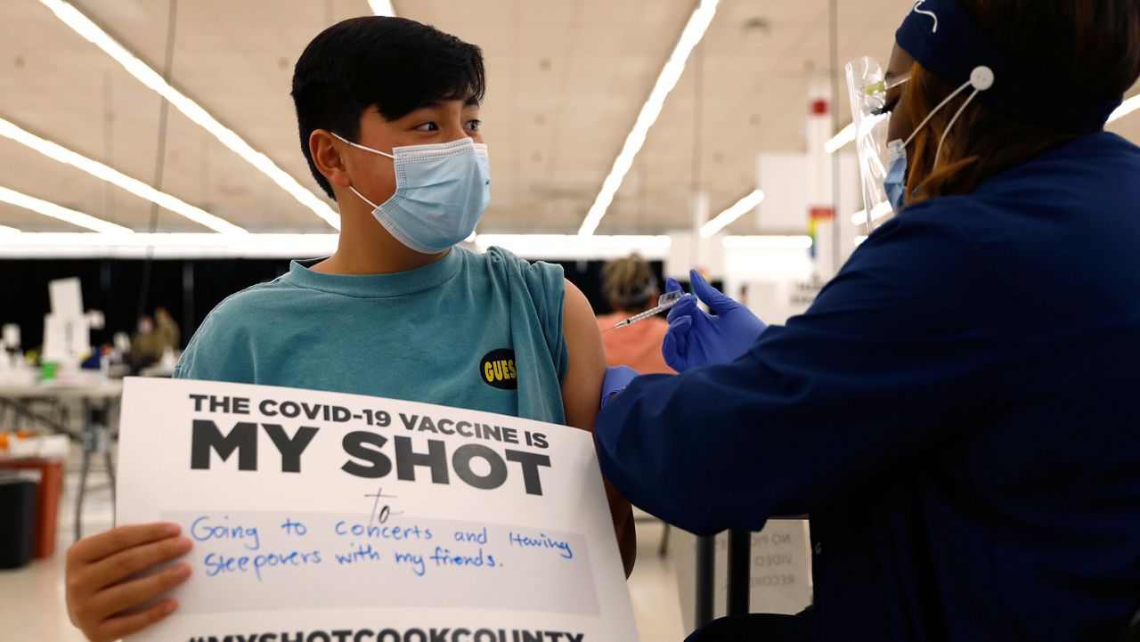 FILE - Lucas Kittikamron-Mora, 13, holds a sign in support of COVID-19 vaccinations as he receives his first Pfizer vaccination at the Cook County Public Health Department, May 13, 2021 in Des Plaines, Ill. (AP Photo/Shafkat Anowar, file)