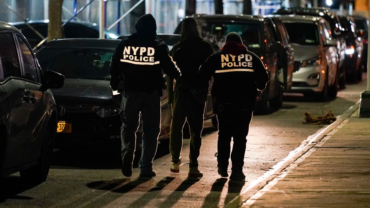 Police officers escort a handcuffed suspect to a car during an operation in the Brooklyn borough of New York on Tuesday, Jan. 4, 2022.