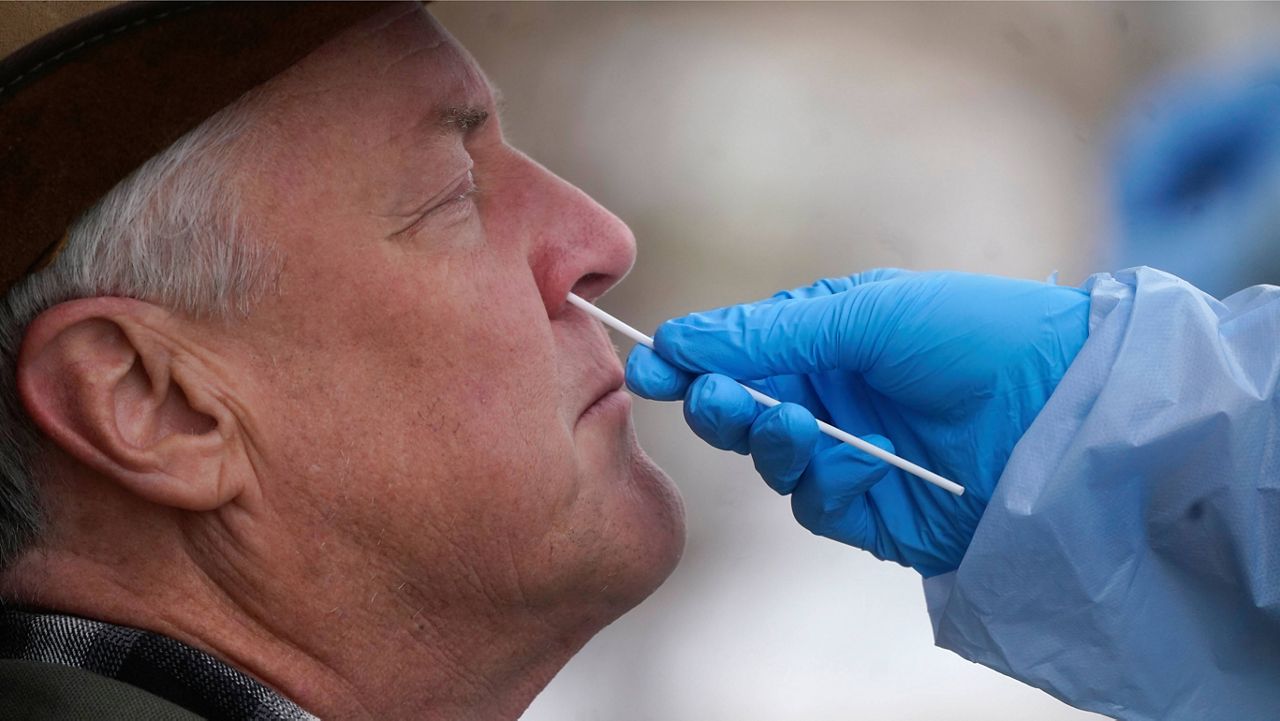 A member of the Salt Lake County Health Department COVID-19 testing staff performs a test on Gary Mackelprang on Tuesday in Salt Lake City. (AP Photo/Rick Bowmer)