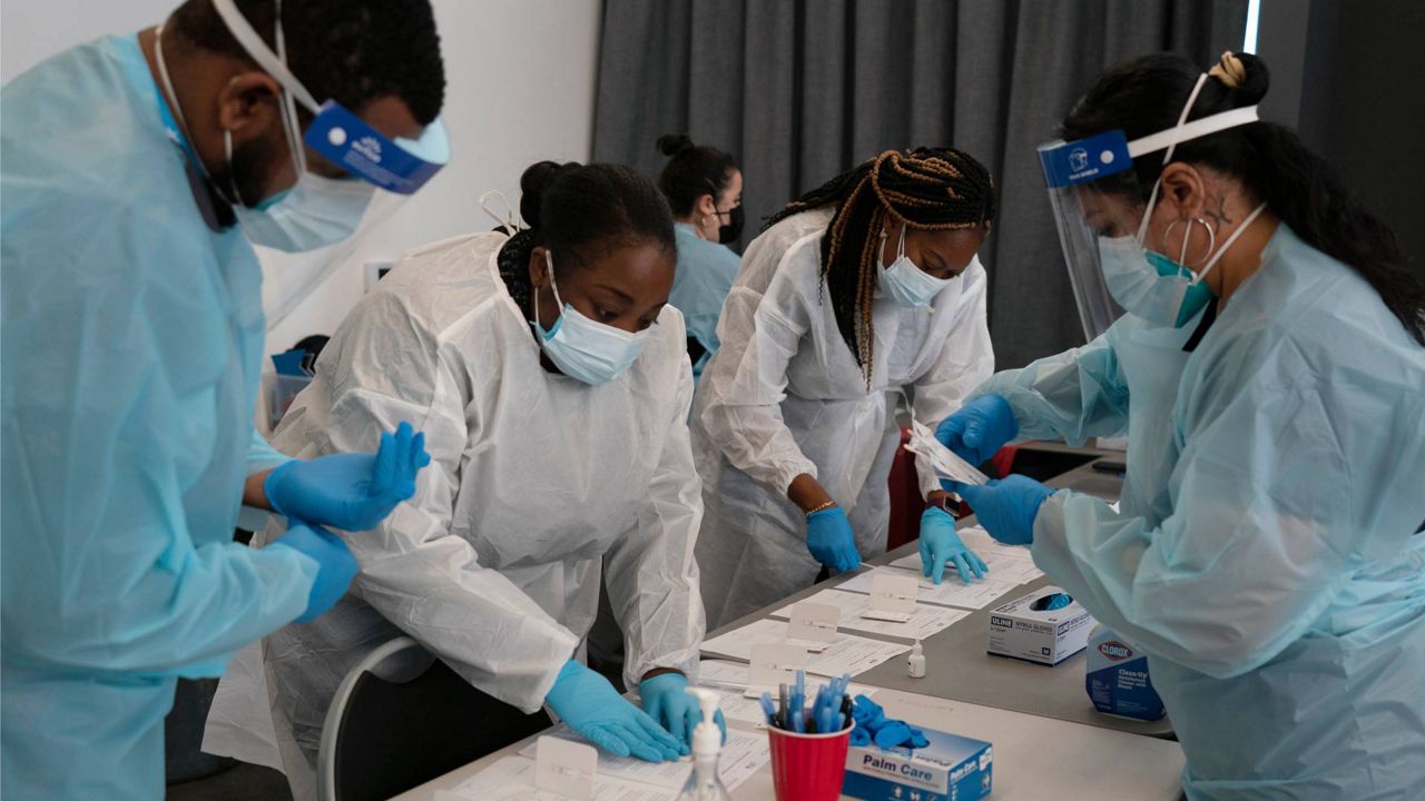 Healthcare workers Henry Paul, from left, Ray Akindele, Wilta Brutus and Leslie Powers process COVID1-9 rapid antigen tests at a testing site in Long Beach , Calif., Jan. 6, 2022. (AP Photo/Jae C. Hong)
