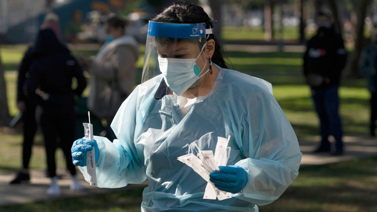 Medical assistant Leslie Powers carries swab samples collected from people to process them on-site at a COVID-19 testing site in Long Beach, Calif., Jan. 6, 2022. (AP Photo/Jae C. Hong)