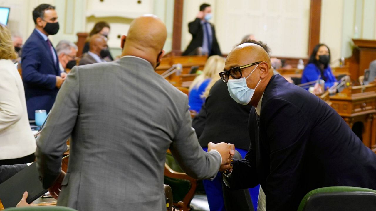 Democratic Assemblyman Chris Holden, right, receives congratulations from fellow Democratic Assemblyman Isaac Bryan, after his fast food employee measure was approved by the Assembly in Sacramento, Calif., Jan. 31, 2022. (AP Photo/Rich Pedroncelli)