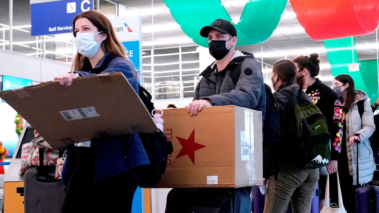 FILE - Travelers line up wearing protective masks indoors at O'Hare International Airport in Chicago, Tuesday, Dec. 28, 2021. (AP Photo/Nam Y. Huh, File)
