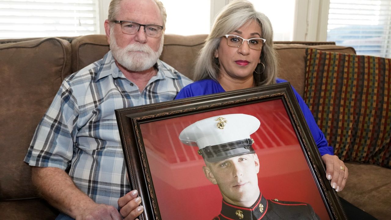 Joey and Paula Reed pose for a photo with a portrait of their son Marine veteran and Russian prisoner Trevor Reed at their home in Fort Worth, Texas, Tuesday, Feb. 15, 2022. (AP Photo/LM Otero)