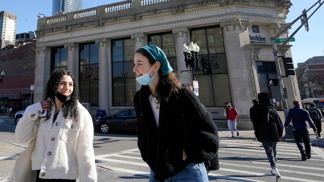 Passersby wear masks under their chins Feb. 9 as they chat with one another while crossing a street in Boston. (AP Photo/Steven Senne, File)