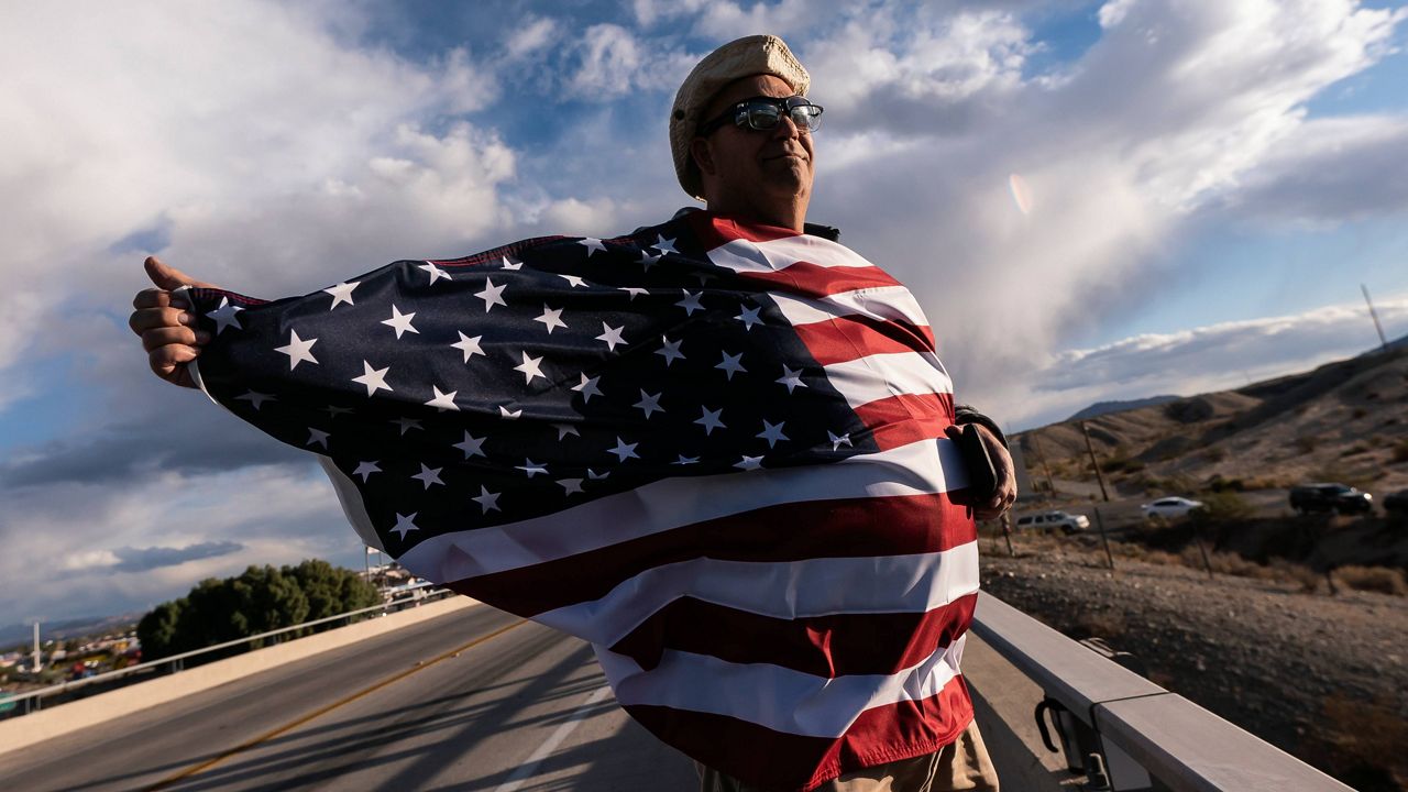 John Hiickman cheers on a convoy of truckers heading toward Washington to protest COVID-19 mandates Wednesday in Needles, Calif. (AP Photo/Nathan Howard, File)