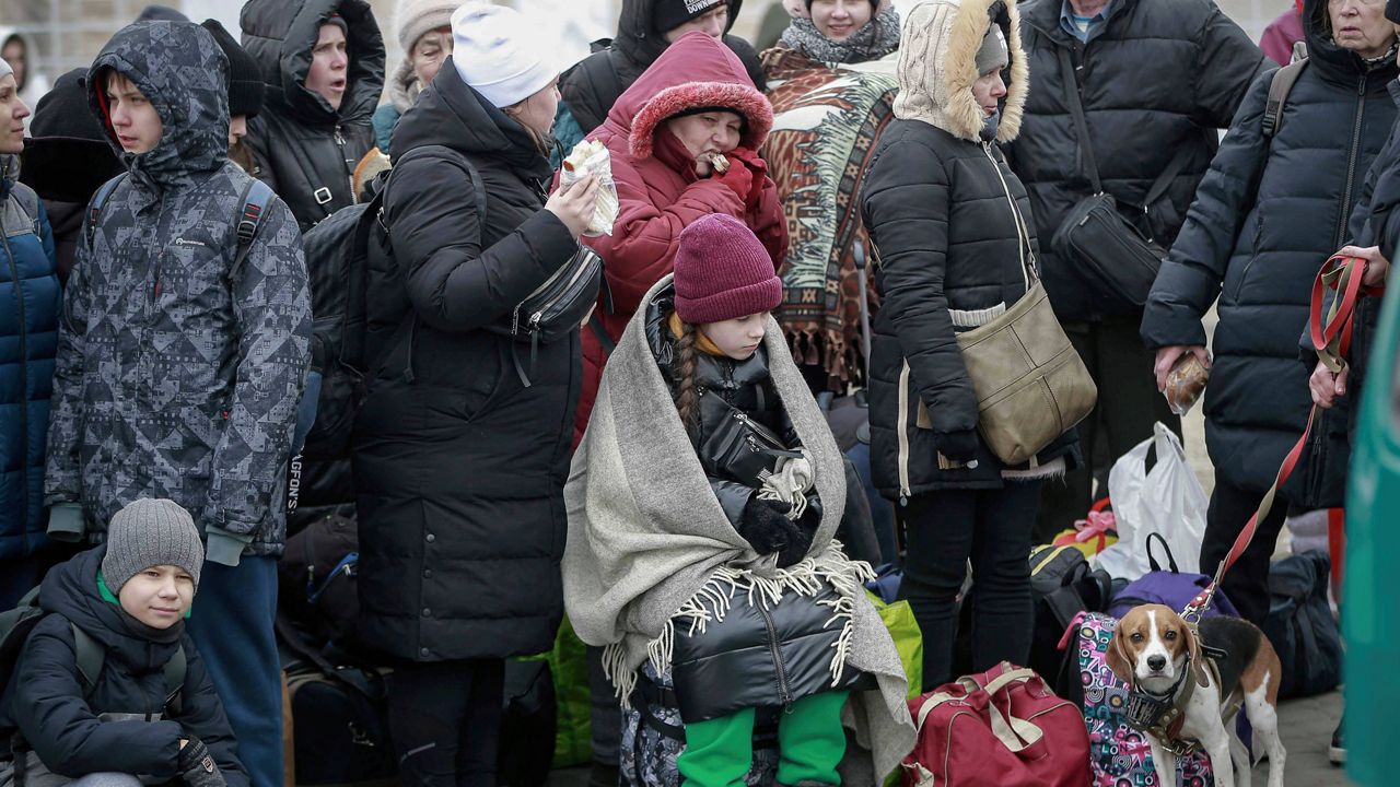 People who left Ukraine wait Friday for a bus to take them to the train station in Przemysl, at the border crossing in Medyka, Poland. (AP Photo/Visar Kryeziu)