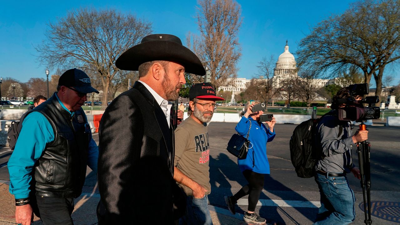 Otero County Commissioner Couy Griffin, center walks from federal court after the first day of his trial, as U.S. Capitol is seen in the background, in Washington, Monday, March. 21, 2022. (AP Photo/Gemunu Amarasinghe)