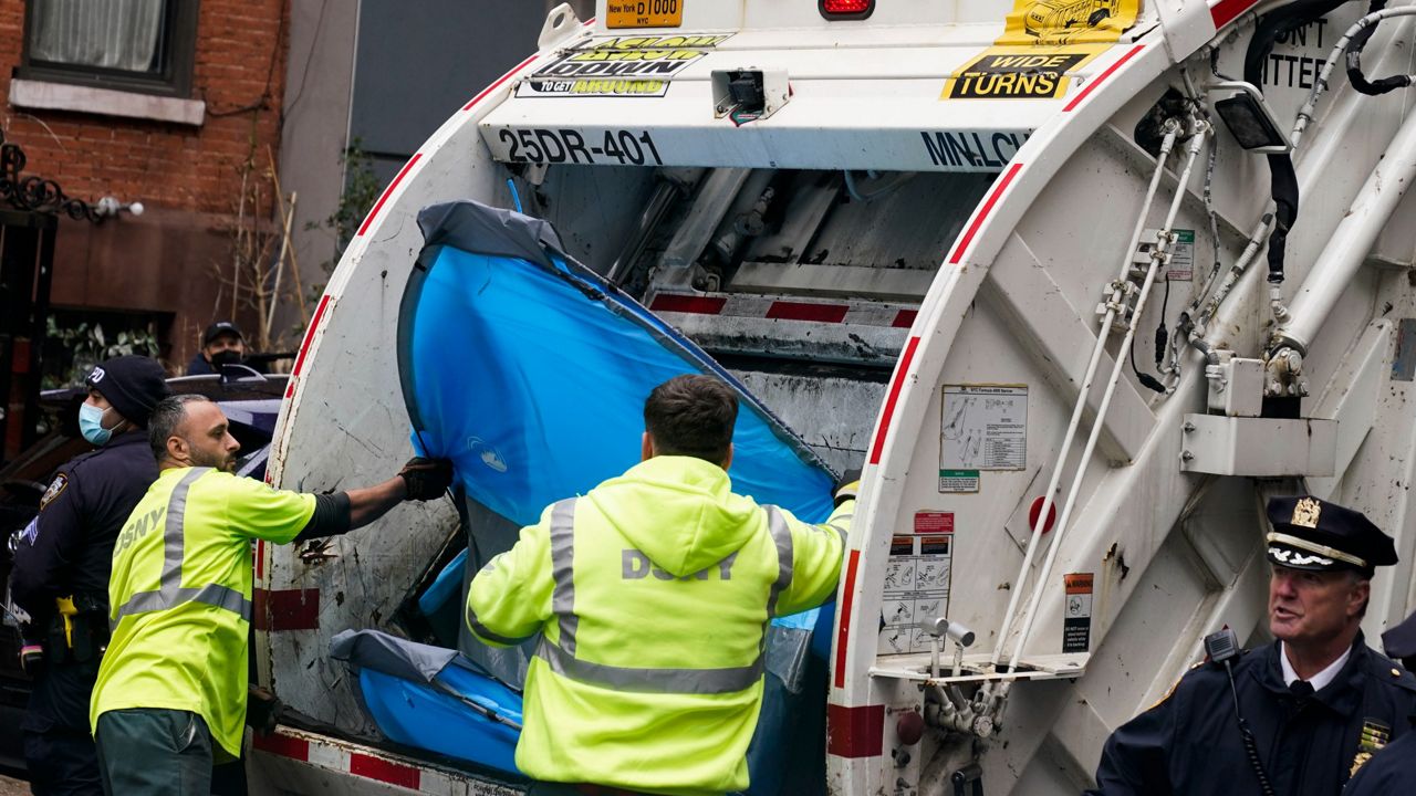 Sanitation workers move a tent to a garbage truck at a small homeless encampment in New York on Wednesday, April 6, 2022. (AP Photo/Seth Wenig)