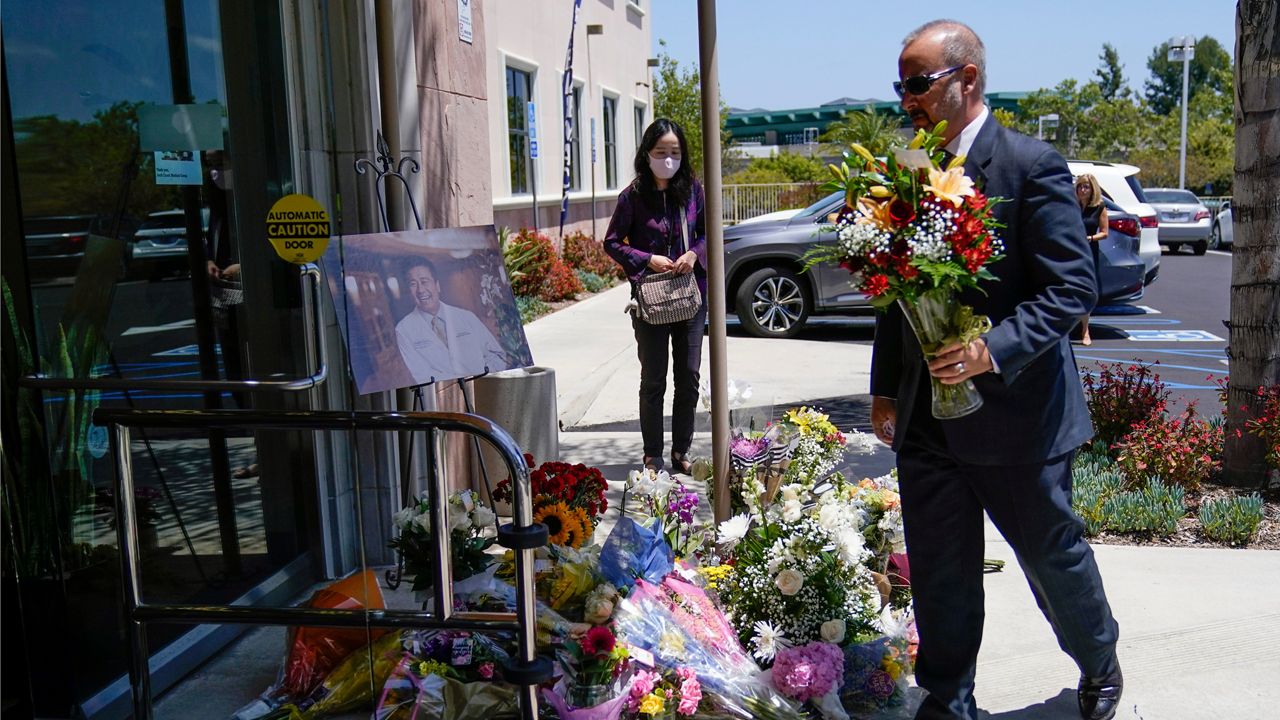 A man places flowers at a memorial honoring Dr. John Cheng sits outside his office building on Tuesday in Aliso Viejo, Calif. Cheng, 52, was killed in Sunday's shooting at Geneva Presbyterian Church. (AP Photo/Ashley Landis)