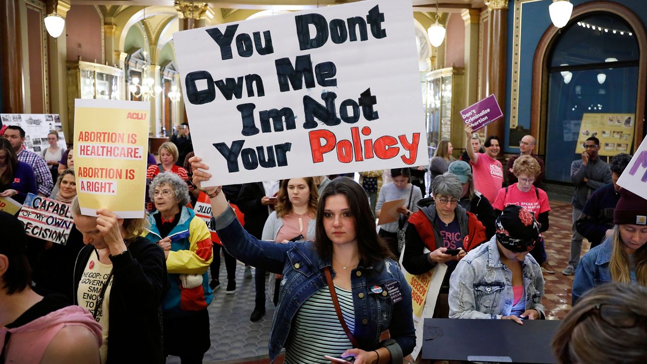 FILE - Marissa Messinger, of Lake View, Iowa, center, holds a sign during a rally to protest recent abortion bans, May 21, 2019, at the Statehouse in Des Moines, Iowa. (AP Photo/Charlie Neibergall, File)