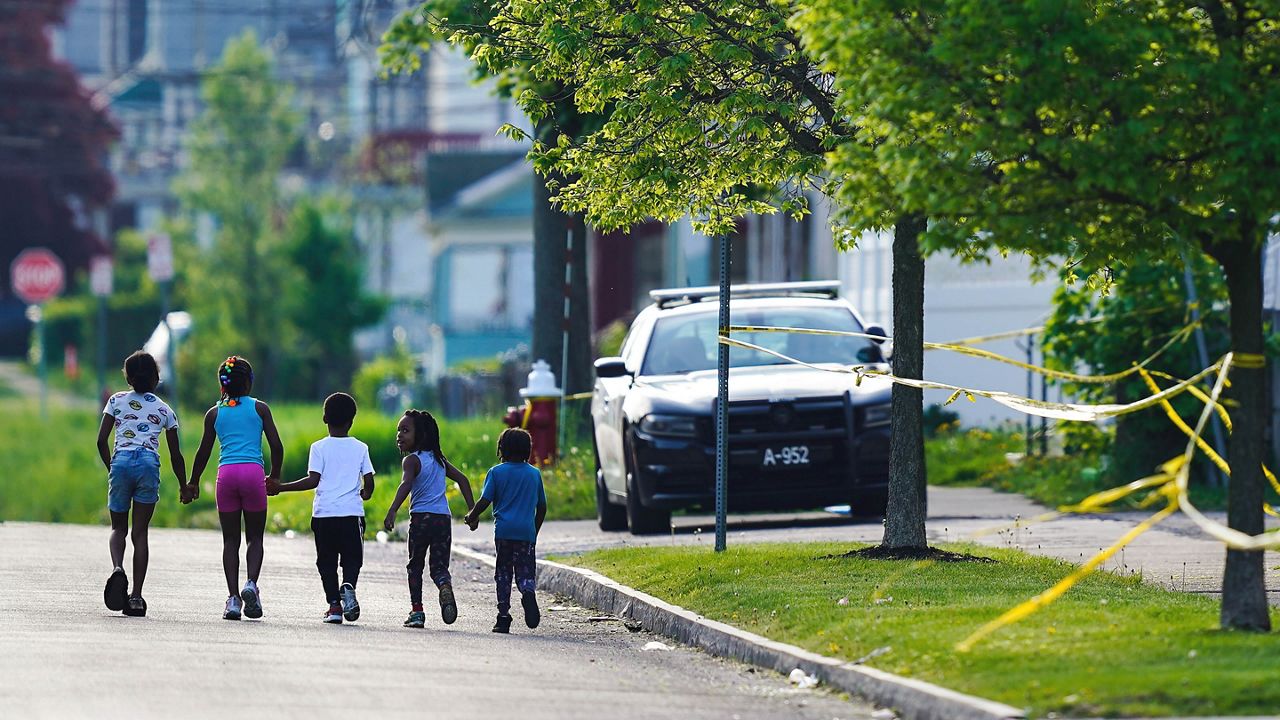 FILE - Children walk hand-in-hand near the scene of a shooting at a supermarket in Buffalo, N.Y., May 15, 2022. The shooting rampage at a Buffalo supermarket, carried out by an 18-year-old who was flagged for making a threatening comment at his high school the year before, highlights concerns over whether schools are adequately supporting and screening students. (AP Photo/Matt Rourke, File)