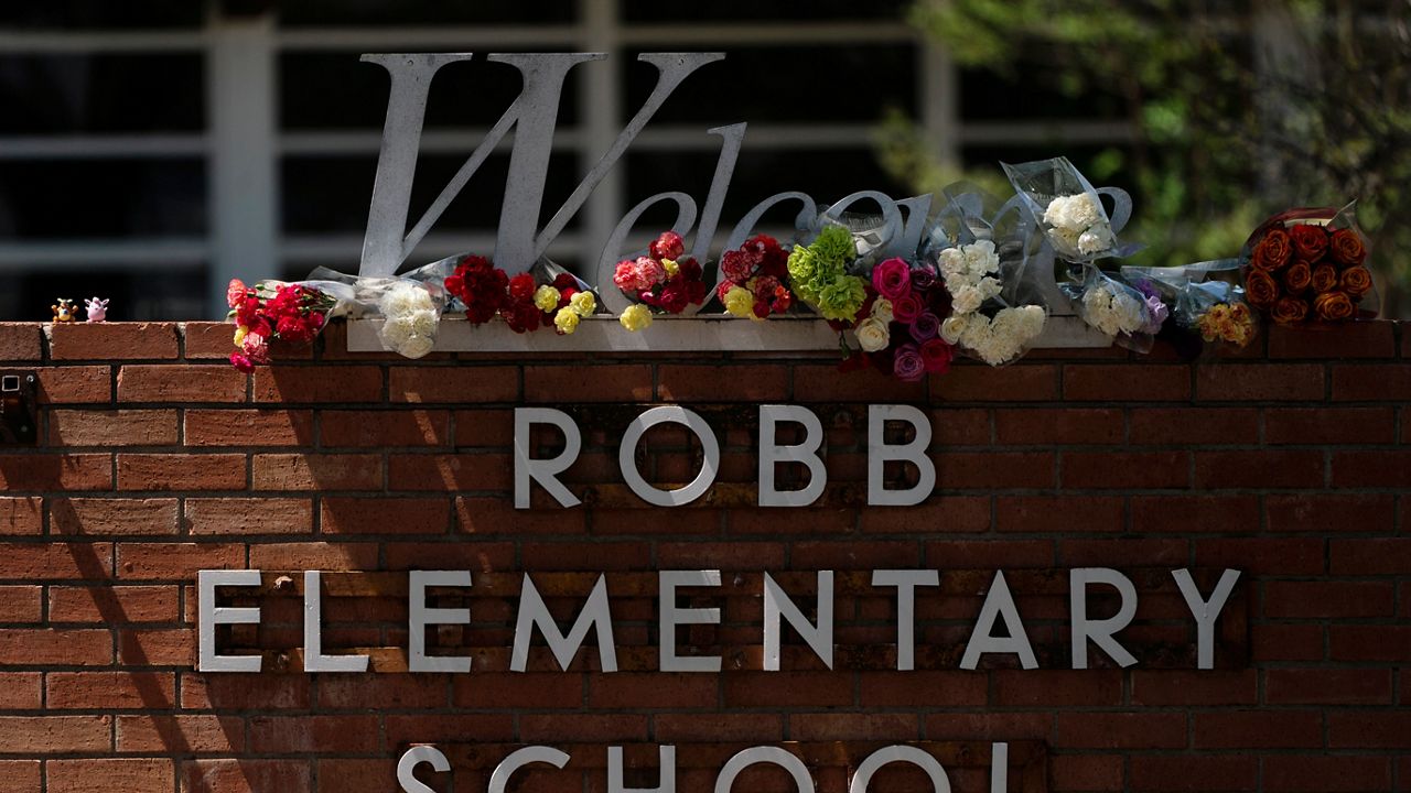 Flowers are placed around a welcome sign outside Robb Elementary School in Uvalde, Texas, Wednesday, May 25, 2022, to honor the victims killed in Tuesday's shooting at the school. (AP Photo/Jae C. Hong)
