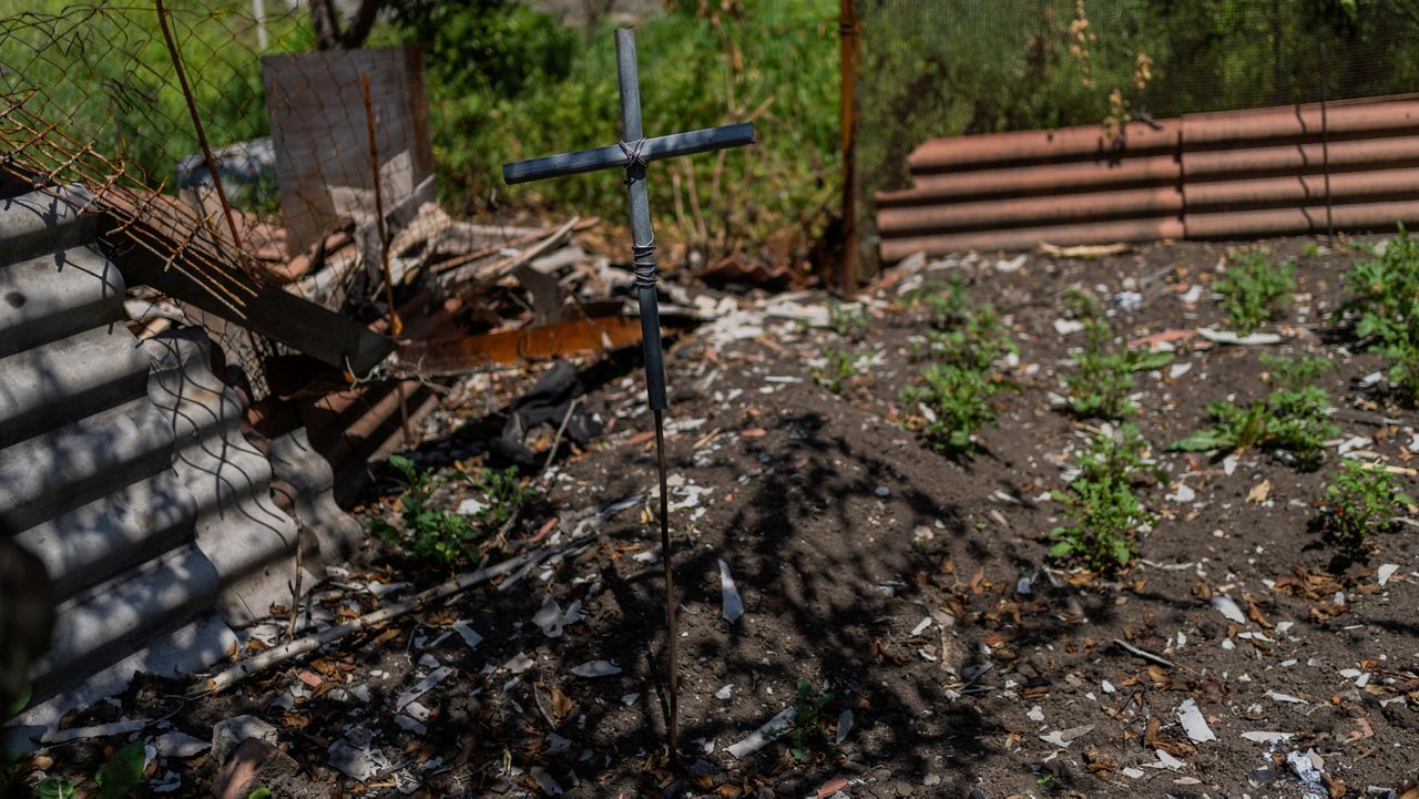 A cross marks the grave of a local resident buried in a courtyard in a village near the frontline in the Donetsk oblast region, eastern Ukraine, Thursday, June 2, 2022. (AP Photo/Bernat Armangue)