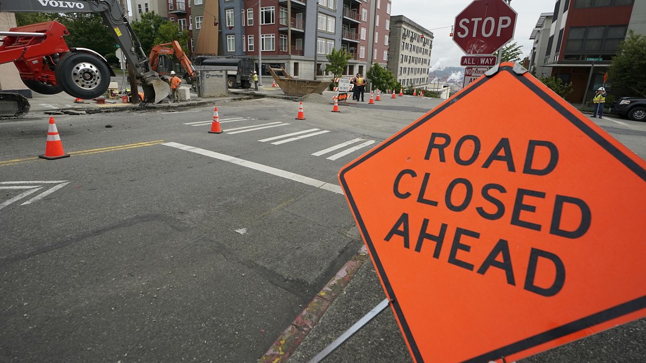 A sign is shown near ongoing work on a project to replace water main pipes, Wednesday, June 15, 2022, in downtown Tacoma, Wash. Inflation is taking a toll on infrastructure projects across the U.S., driving up costs so much that state and local officials are postponing projects, scaling back others and reprioritizing their needs. (AP Photo/Ted S. Warren)