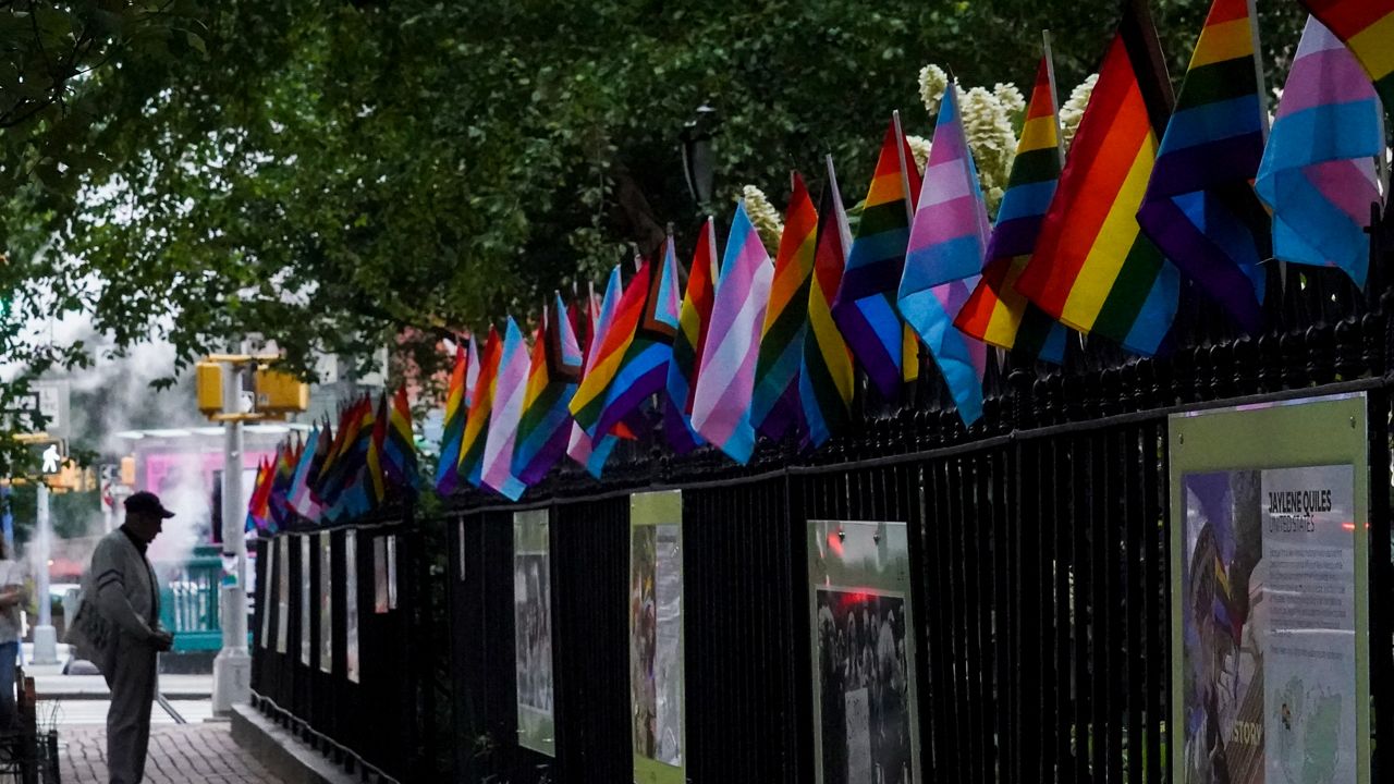 A visitor views a historical exhibit of the Gay rights movement, displayed on fencing dressed with flags affirming LGBTQ identity at the Stonewall National Monument, Wednesday, June 22, 2022, in New York.