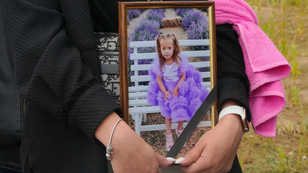 A woman carries a portrait of Liza, a 4-year-old girl killed by Russian attack, during a funeral ceremony in Vinnytsia, Ukraine on Sunday, July 17, 2022. Wearing a blue denim jacket with flowers, Liza was among 23 people killed, including two boys aged 7 and 8, in Thursday's missile strike in Vinnytsia. Her mother, Iryna Dmytrieva, was among the injured.