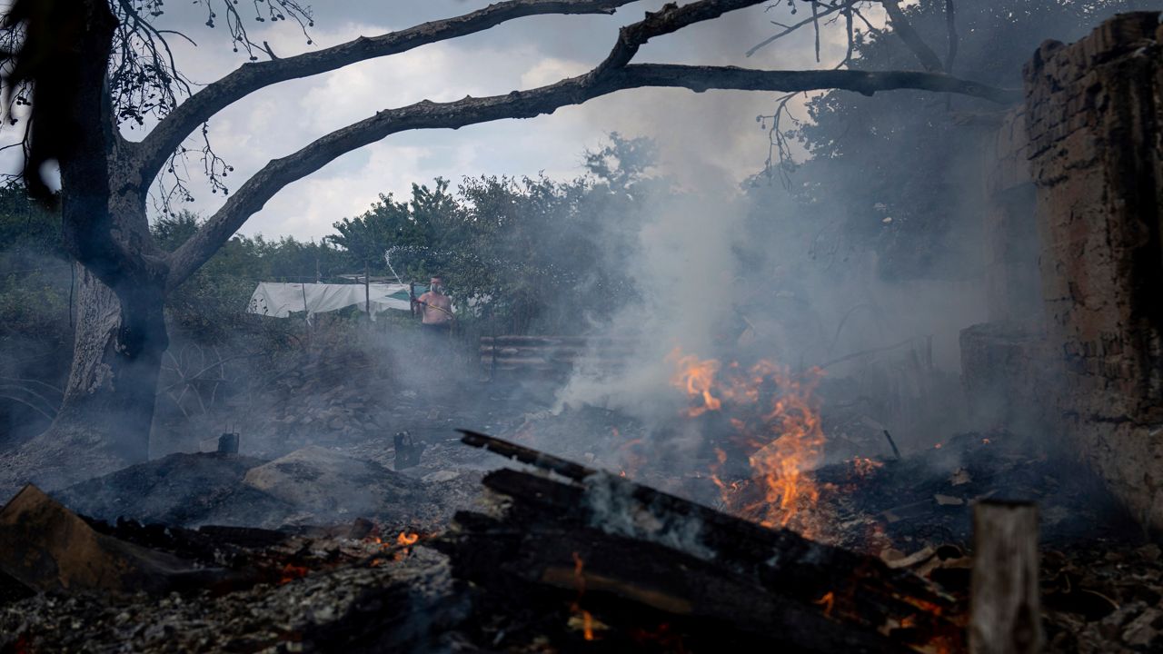 A local resident, back, tries to stop the fire at a neighbor's house destroyed by a Russian attack in Mykolaiv, Ukraine, Friday, Aug. 5, 2022. (AP Photo/Evgeniy Maloletka)