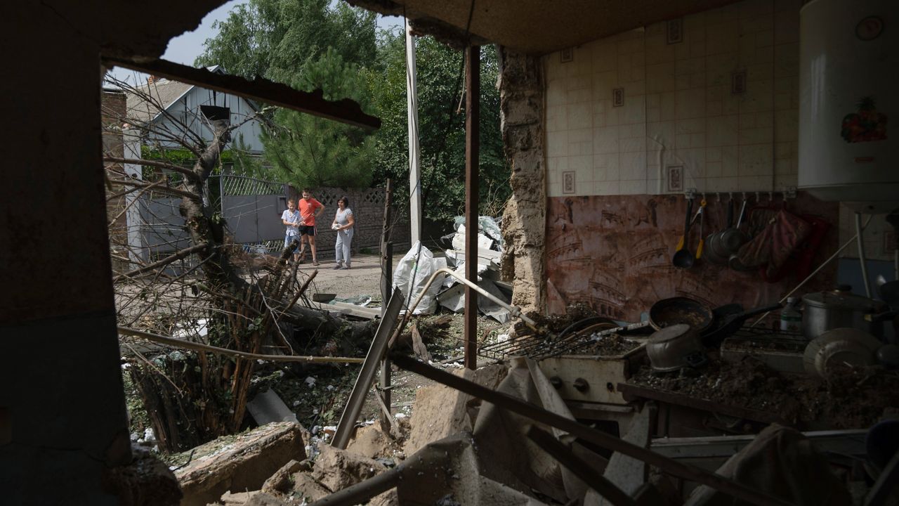 People look on a house which was damaged after Russian bombardment of residential area in Nikopol, Ukraine, on Monday, Aug, 22, 2022. (AP Photo/Evgeniy Maloletka)