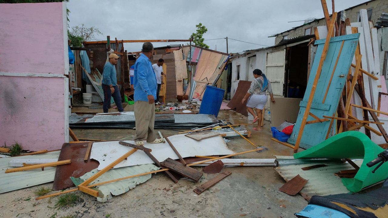 Residents stand amid their homes that were damaged by Hurricane Fiona in the low-income neighborhood of Kosovo in Veron de Punta Cana, Dominican Republic, Monday, Sept. 19, 2022. (AP Photo/Ricardo Hernandez)