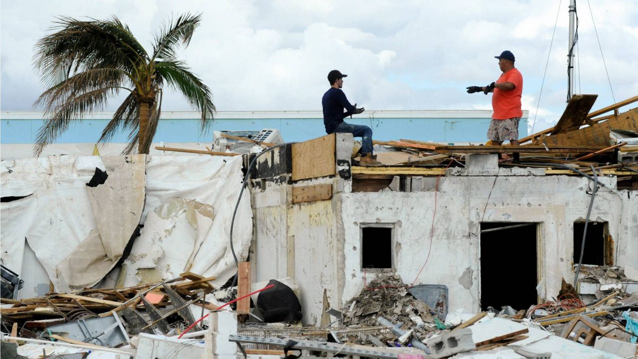 Workers talk atop a building that was heavily damaged by Hurricane Ian at Fort Myers Beach, Fla., on Sunday, Oct. 9, 2022. (AP Photo/Jay Reeves)