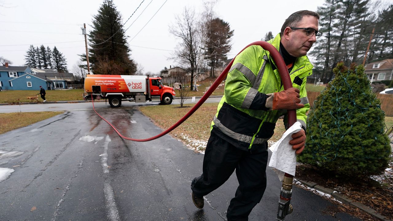FILE - Daniel DiDonato, a deliveryman for Heatable, brings heating oil to a home in Lewiston, Maine, Thursday, Dec. 16, 2021. (AP Photo/Robert F. Bukaty, File)