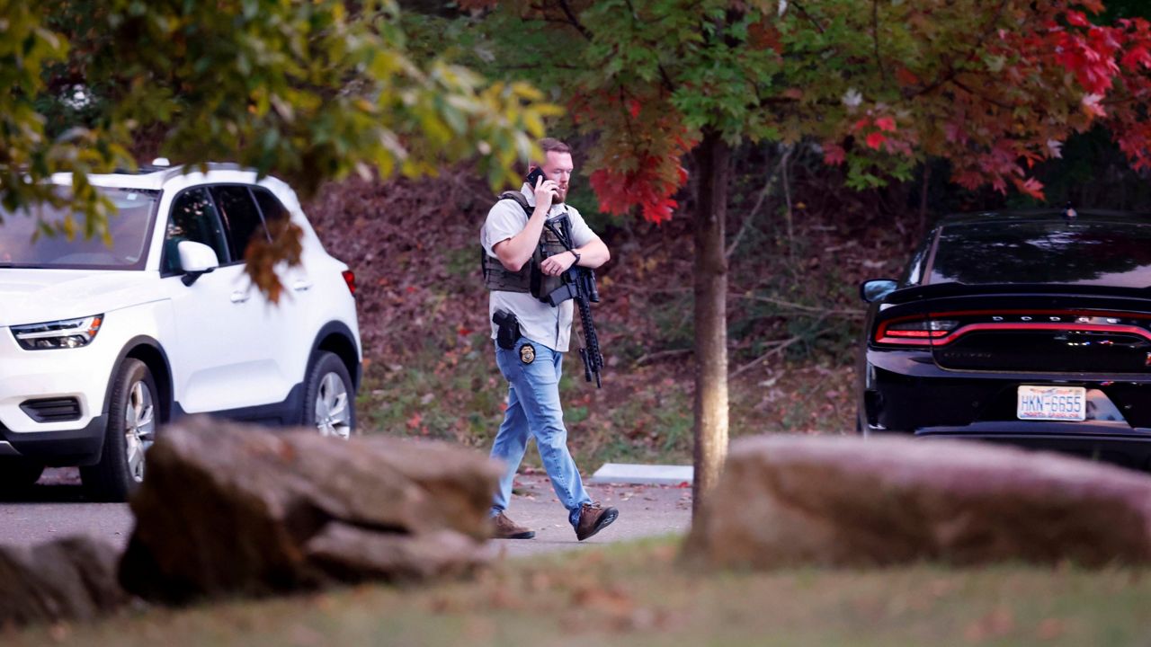 Law enforcement officer walks at the entrance to Neuse River Greenway Trail parking at Abington Lane following a shooting in Raleigh, N.C., Thursday, Oct. 13, 2022. (Ethan Hyman/The News & Observer via AP)