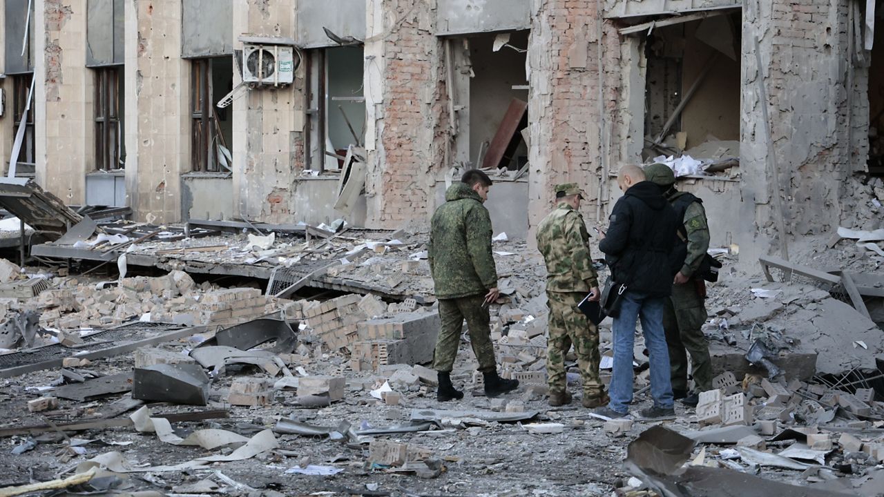 Investigators inspect a site after shelling near an administrative building, in Donetsk, the capital of Donetsk People's Republic, eastern Ukraine, Sunday, Oct. 16, 2022. According to the Donetsk People's Republic's (DPR) mission to the Joint Center for Control and Coordination, six 155mm munitions were fired at Donetsk in the early hours of Sunday. (AP Photo/Alexei Alexandrov)